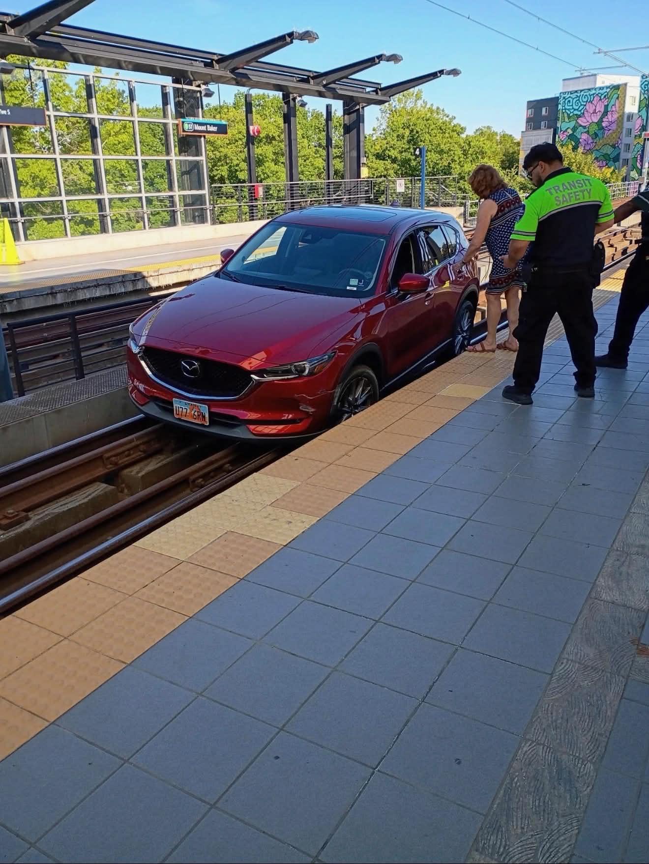 A red car on the rail track in a station